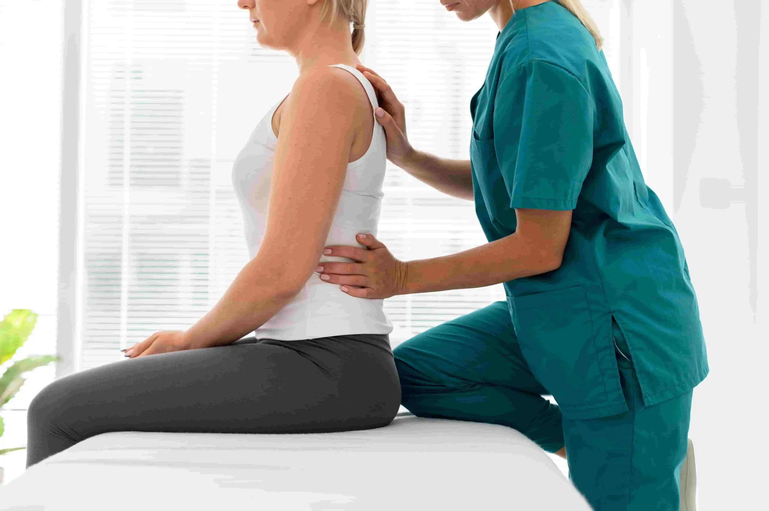 Chiropractor assessing spinal alignment while a patient sits on an exam table