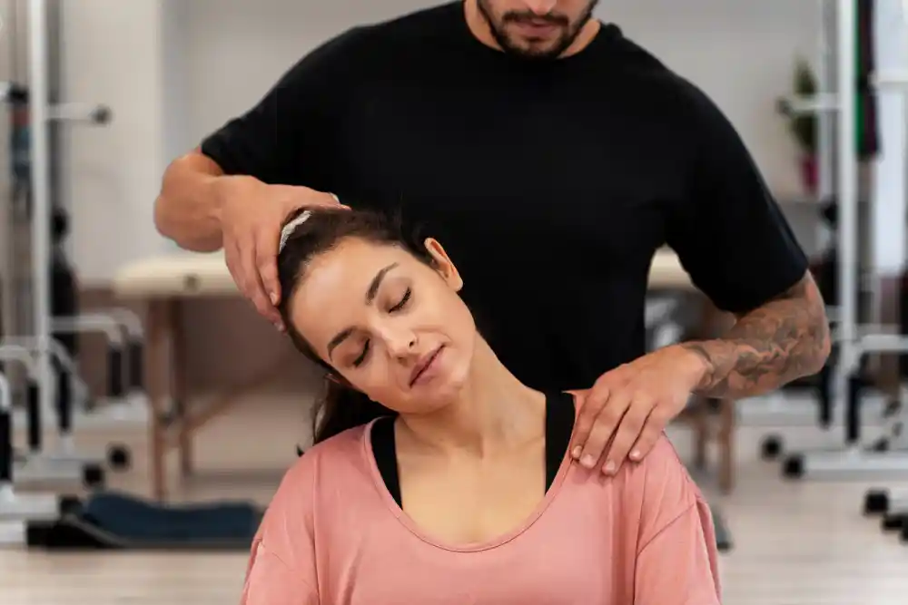 A therapist gently stretches a woman’s neck during a treatment session.