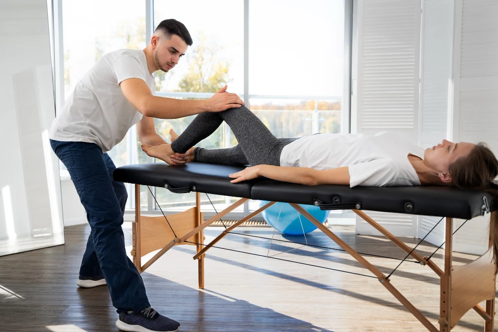 Chiropractor performing rehabilitation therapy on female patient lying down
