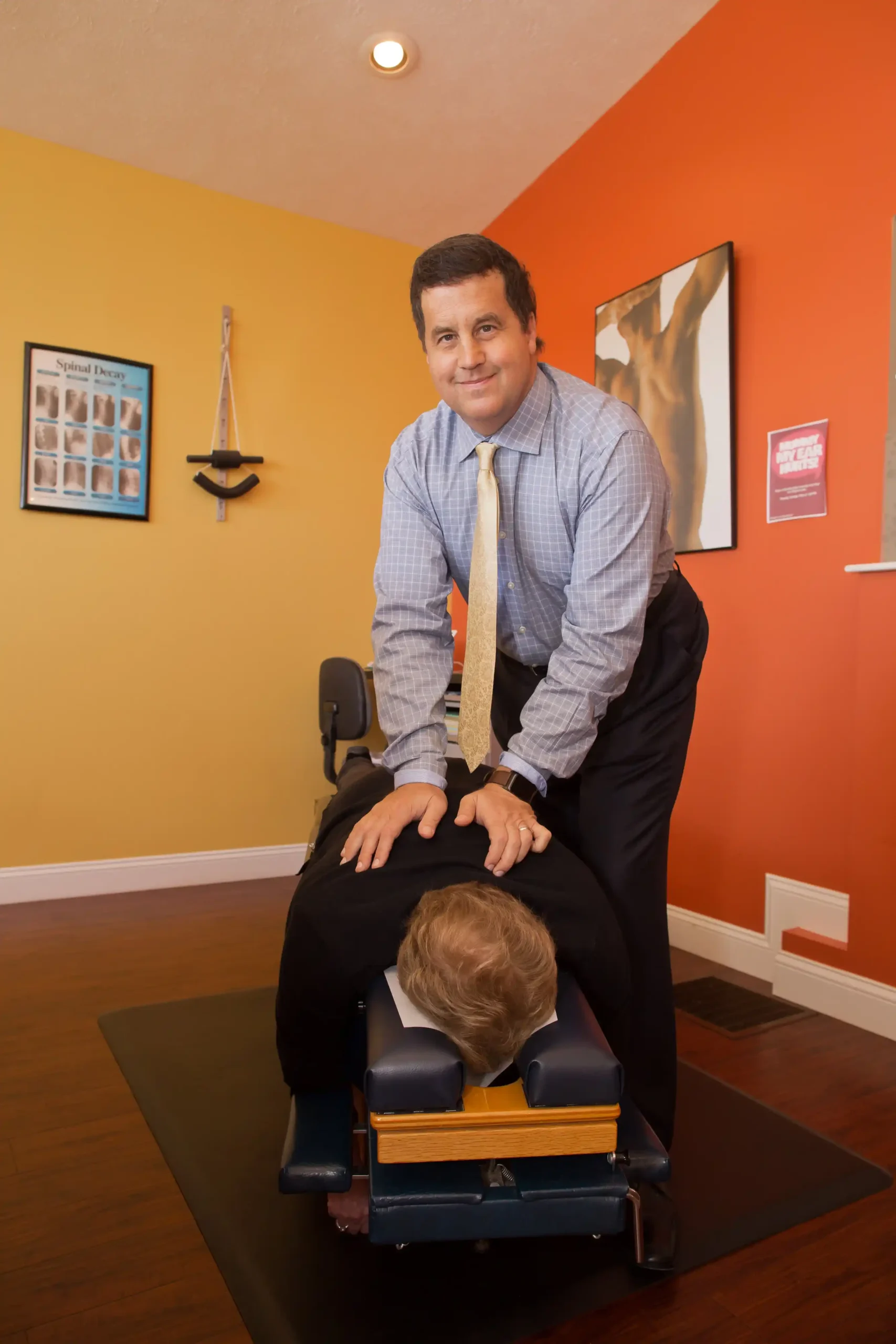 Chiropractor performing a spinal adjustment on a patient in a treatment room.