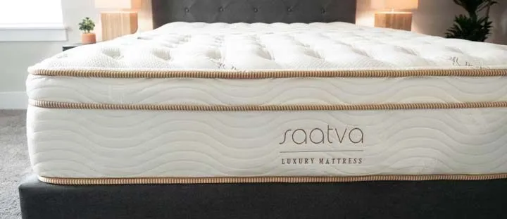 Saatva luxury mattress displayed on a bed with quilted top and upholstered headboard