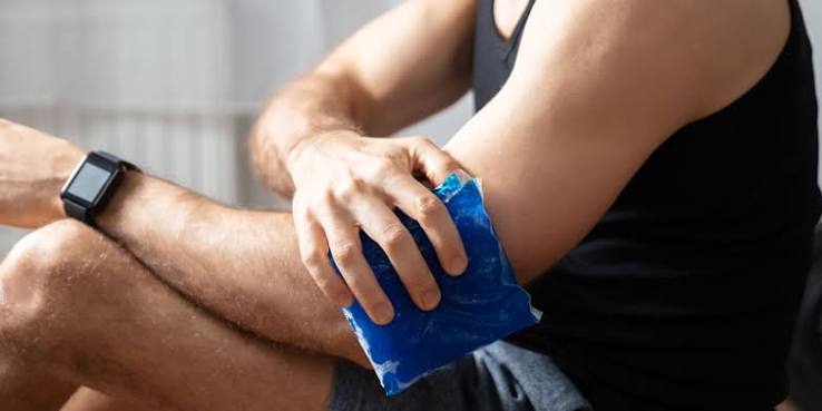 Person applying an ice pack to a sore knee to reduce pain and inflammation after an injury.
